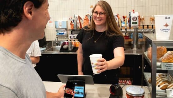 Sophia Goldberg handing a customer a cup of coffee.