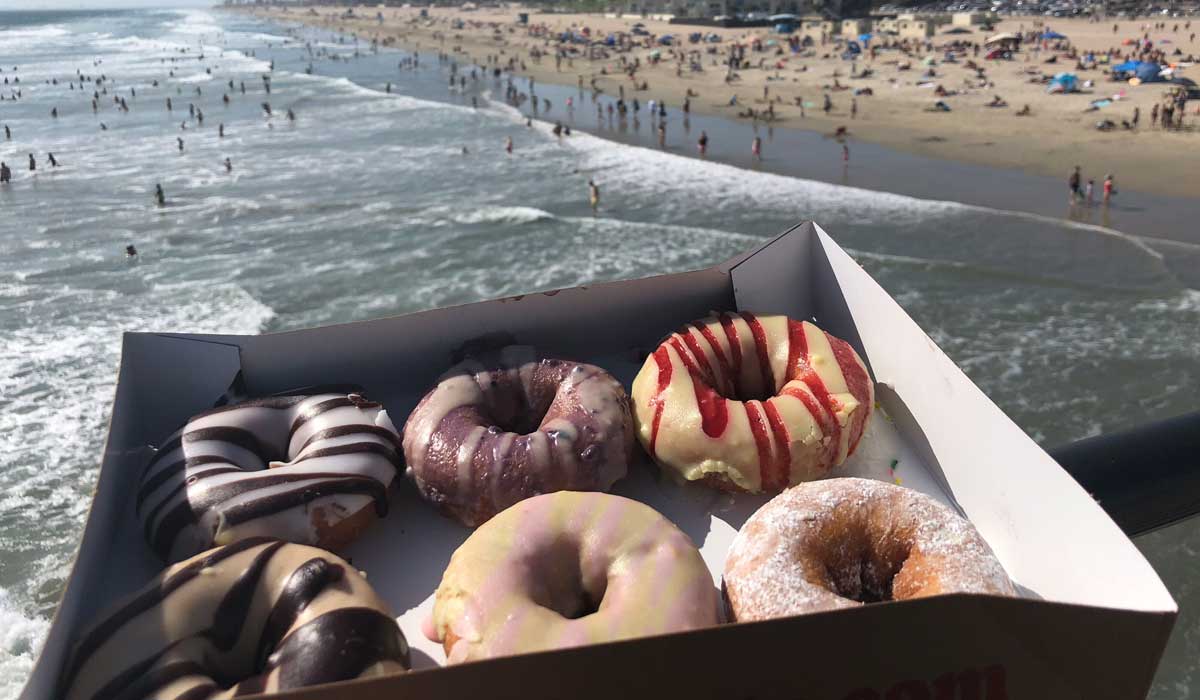 A Box Of Duck Donuts With The Beach In The Background