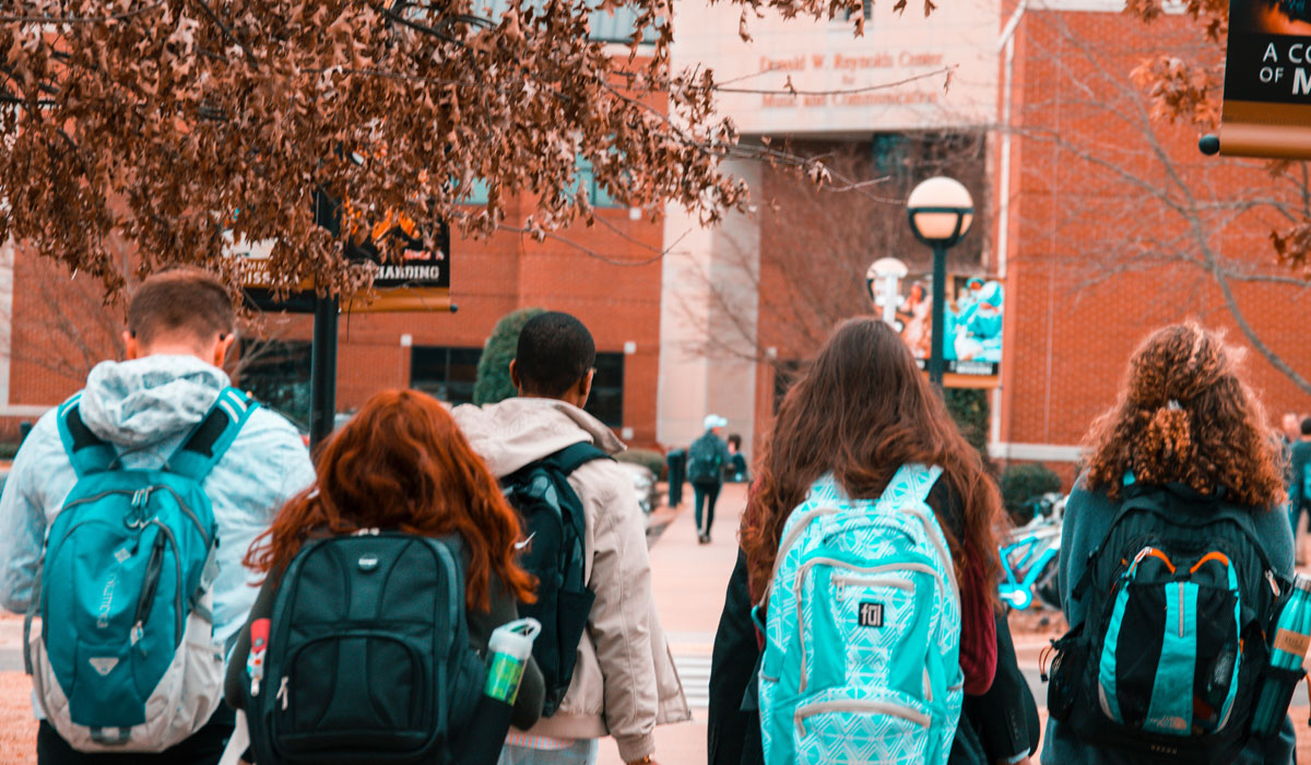 College Students Walk To Class With Their Backpacks On