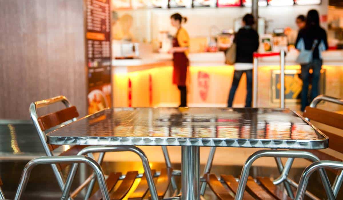 Empty chairs and table next to a fast food restaurant.