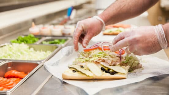 An employee making a sandwich at Port of Subs.