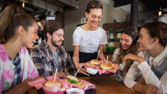 Restaurant server bringing food to a table.