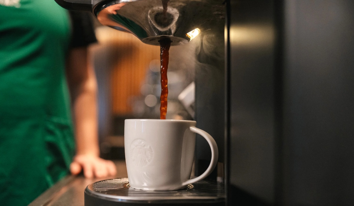 Coffee being poured into a Starbucks cup.